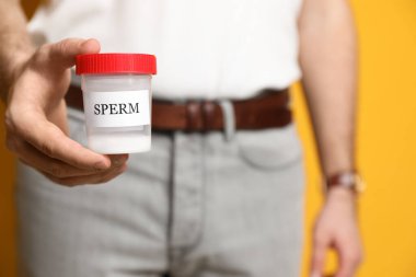 Donörün elinde sperm kabı var. Yakın çekim görüntüsü.