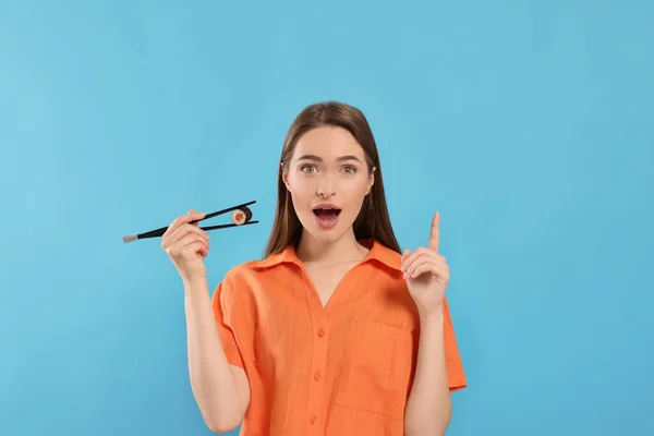 Jovem Mulher Emocional Segurando Rolo Sushi Com Pauzinhos Fundo Azul — Fotografia de Stock