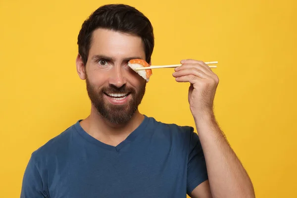 Vtipný Muž Drží Sushi Hůlkami Oranžovém Pozadí — Stock fotografie