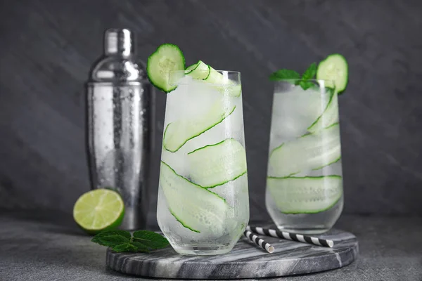 Glasses of refreshing cucumber water on dark grey table