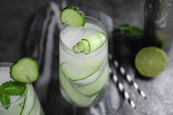 Refreshing cucumber water on dark grey table, closeup