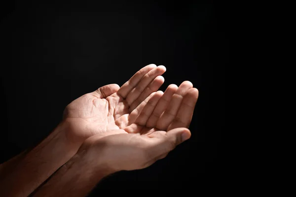 Man reaching hands to light in darkness, closeup