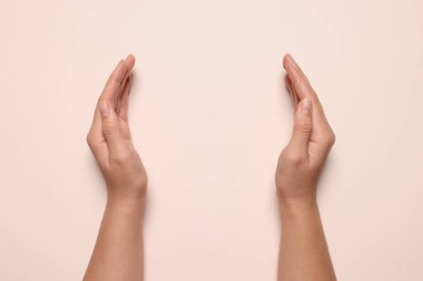 Soluk pembe arka planı olan bir kadın, elleri yakın çekim. Metin için boşluk