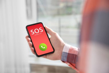 Elinde acil yardım çağrısı olan akıllı telefonu olan bir adam var. Kapalı alanda, kapalı alanda.