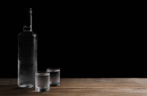 Botella Vodka Vasos Chupito Sobre Mesa Madera Sobre Fondo Negro —  Fotos de Stock