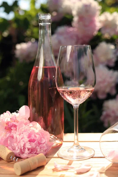 Μπουκάλι Και Ποτήρι Ροζέ Κρασί Κοντά Όμορφες Παιώνιες Ξύλινο Τραπέζι — Φωτογραφία Αρχείου