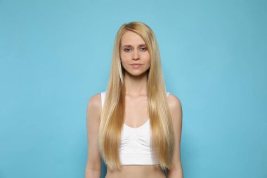 Açık mavi arka planda uzun düz saçlı güzel bir genç kadın.