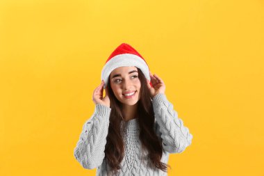 Sarı arka planda Noel Baba şapkası takan güzel kadın.