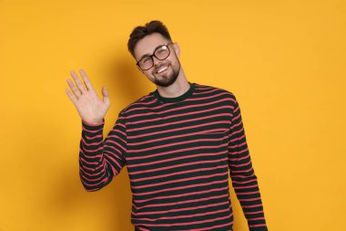 Sarı arka planda çizgili sweatshirt ve gözlüklü yakışıklı bir adam.