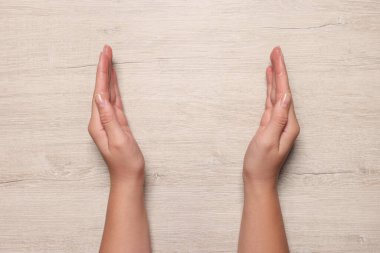 Beyaz ahşap masada oturan kadın, elleri yakın çekim. Metin için boşluk