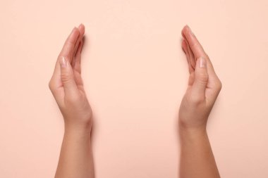 Soluk pembe arka planı olan bir kadın, elleri yakın çekim. Metin için boşluk