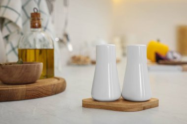 Ceramic salt and pepper shakers on white countertop in kitchen, space for text