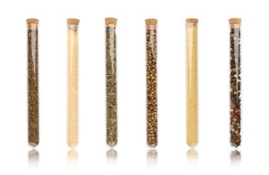 Beyaz zemin üzerinde farklı baharatlar bulunan cam tüpler.