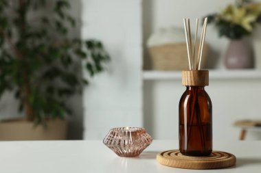 Aromatik kamış oda spreyi ve beyaz masadaki mum. Metin için boşluk