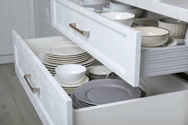 Mutfakta farklı tabak ve kaseleri olan çekmeceleri aç, kapat.