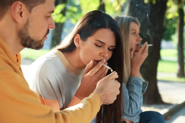 People smoking cigarettes outdoors on sunny day