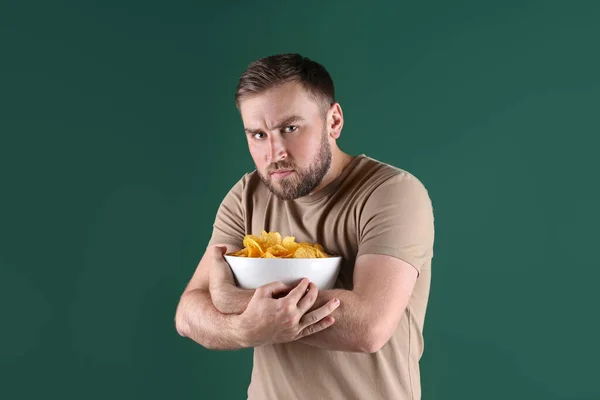 Greedy Young Man Hiding Bowl Chips Green Background — Stock Photo, Image