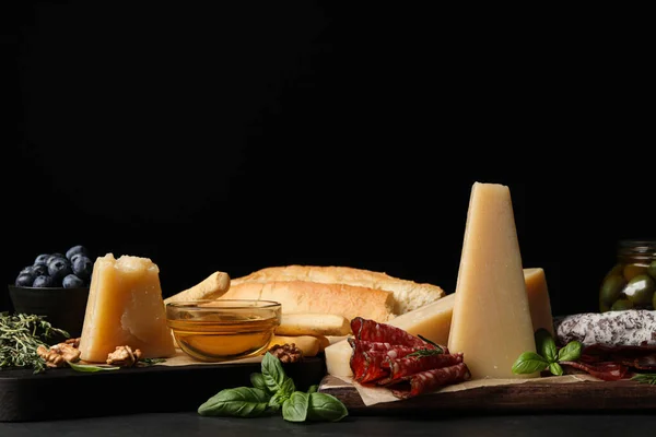 Delicious parmesan cheese, sausage slices, honey, bread and basil on grey table