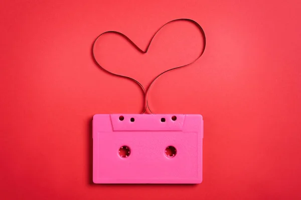 Music cassette and heart made with tape on red background, top view. Listening love song