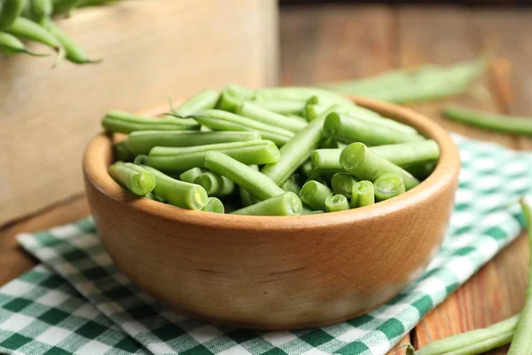 Fresh green beans in bowl on wooden table, closeup