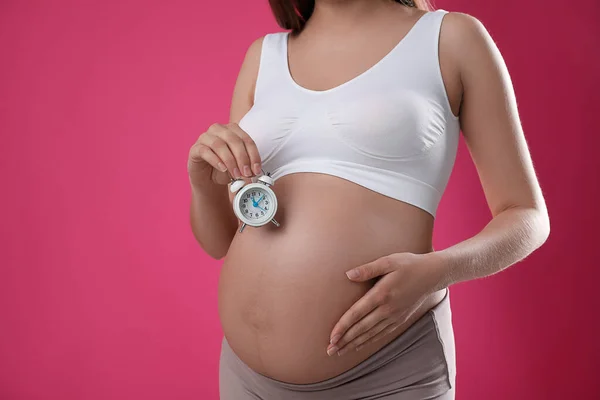 Νεαρή Έγκυος Γυναίκα Κρατώντας Ξυπνητήρι Κοντά Στην Κοιλιά Της Ροζ — Φωτογραφία Αρχείου
