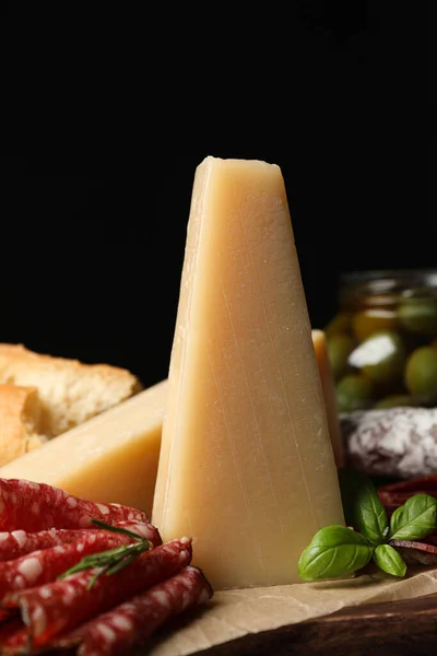 Delicious parmesan cheese, sausage slices, honey and basil on wooden board, closeup