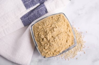 Cam kasede susam unu, beyaz mermer masa, üst manzara.