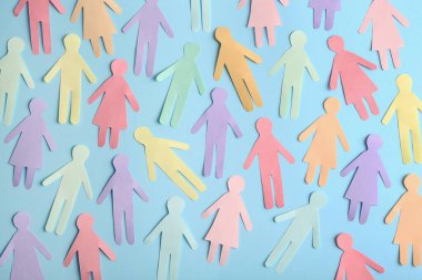 Many different paper human figures on light blue background, flat lay. Diversity and inclusion concept