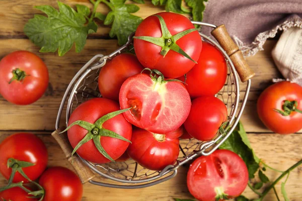 Fresh ripe tomatoes with leaves on wooden table, flat lay
