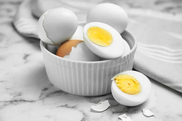 Bowl with hard boiled eggs on white marble table