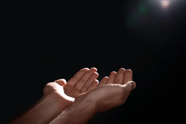 Man reaching hands to light in darkness, closeup