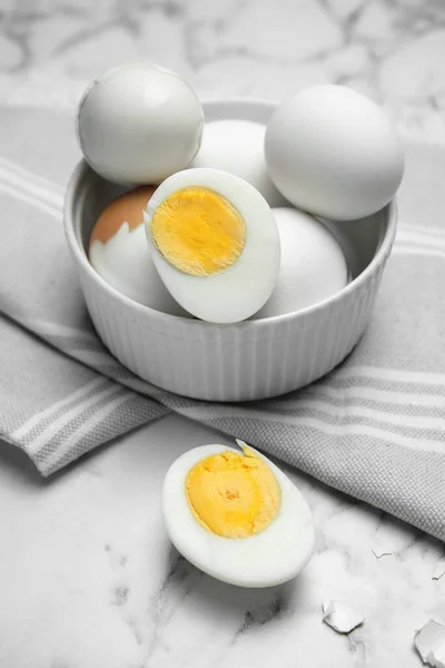 Bowl with hard boiled eggs on white marble table