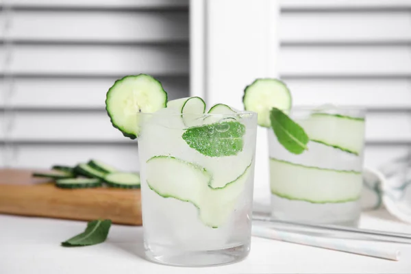 Tasty fresh cucumber water with mint on white wooden table