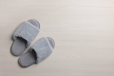 Beyaz ahşap zeminde bir çift yumuşak terlik, üst manzara. Metin için boşluk