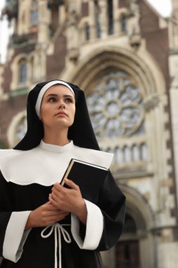 Katedralin yanında İncil 'i olan genç bir rahibe.