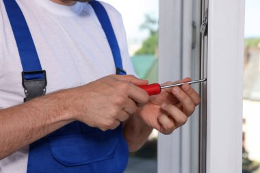 Worker adjusting installed window with screwdriver indoors, closeup