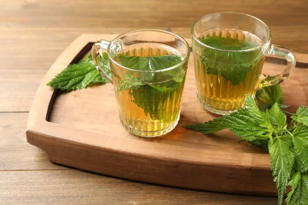 Glas Koppar Aromatiska Nässlor Och Gröna Blad Träbord — Stockfoto