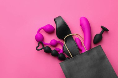Pembe arka planda farklı seks oyuncakları olan bir alışveriş çantası. Metin için boşluk