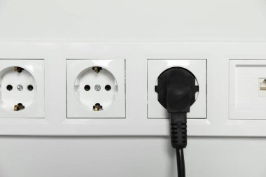 Elektrik prizleri beyaz duvara takılı, yakın plan. Elektrik arzı