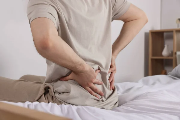 部屋のベッドに座っている間 背中の痛みに苦しむ男 クローズアップ 大腸炎の症状 — ストック写真
