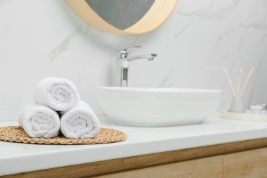 Banyodaki beyaz masanın üzerine sarılmış banyo havluları, mesaj için yer.