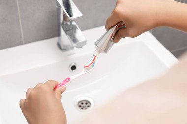 Banyoda diş fırçasına diş macunu süren kadın, yakın plan.