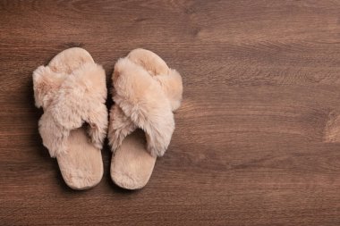 Ahşap zeminde bir çift yumuşak terlik, üst manzara. Metin için boşluk