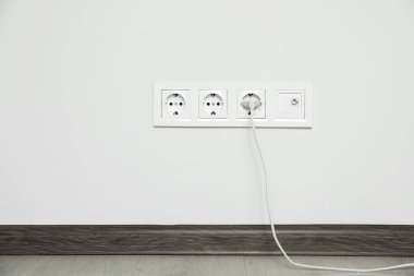 İçerideki beyaz duvarda prize takılmış güç prizleri. Elektrik arzı