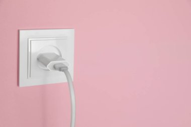 Pembe duvardaki güç prizine bağlı şarj adaptörü, mesaj için boşluk. Elektrik arzı