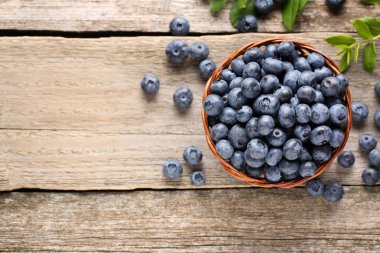 Tasty fresh blueberries on wooden table, flat lay. Space for text