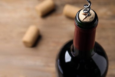 Opening wine bottle with corkscrew on table, closeup. Space for text