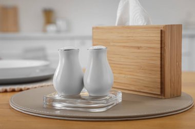 White ceramic salt and pepper shakers on wooden table