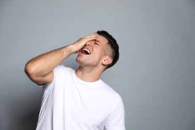 Gri arka planda gülen yakışıklı bir adam. Komik şaka.