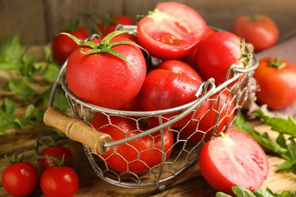Fresh ripe tomatoes with leaves on wooden table, closeup